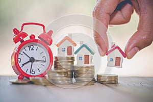 Woman hand hold a home model put on the stack coin with growing in the public park, Savings money for buy house and loan to