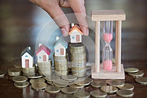 Woman hand hold a home model put on the stack coin with growing in the public park, Savings money for buy house and loan to
