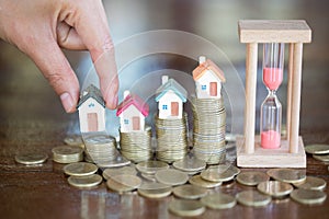 Woman hand hold a home model put on the stack coin with growing in the public park, Savings money for buy house and loan to