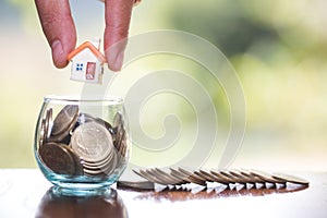 Woman hand hold a home model put on the stack coin with growing, Savings money for buy house and loan to business investment for
