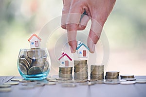 Woman hand hold a home model put on the stack coin with growing, Savings money for buy house and loan to business investment for