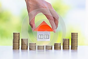 Woman hand hold a  home model put on the stack coin with growing, Savings money for buy house and loan to business investment for
