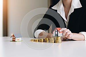 Woman hand hold a home model put on the stack coin with growing. Savings money for buy house and loan to business investment for