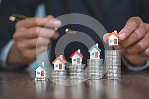 Woman hand hold a  home model put on the stack coin with growing, Savings money for buy house and loan to business investment for