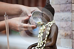 Woman hand hold little bowl to bath Buddha statue