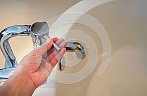 Woman hand hold luxury bathtub faucet in the bathroom