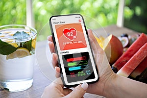 woman hand hold phone with app heart and activity screen