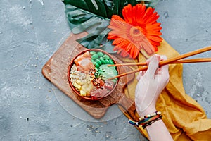 Woman hand hold Poke bowl, traditional Hawaiian raw fish salad with rice,