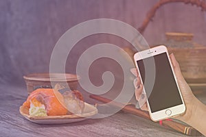 Woman hand hold smart phone on blurred japanese sushi set