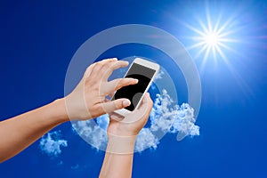 Woman hand hold and touch screen smart phone on blue sky background