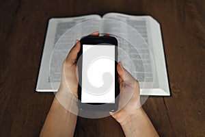 Woman hand hold and touch screen smart phone,cellphone in church over blurred bible holy and age book