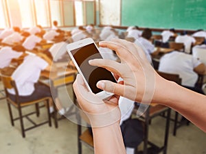 Woman hand hold and touch screen smart phone on students sleeping in classroom background.