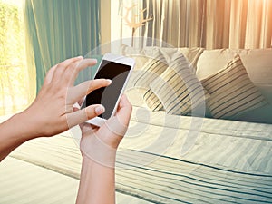 Woman hand hold and touch screen smart phone on vintage bedroom