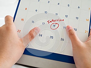 Woman hand hold white calendar with red interview word marked on calendar. Important interview meeting with potential new employer