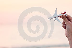 Woman hand holding airplane model in sunset sky and summer sea b