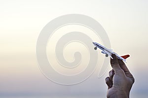 Woman hand holding airplane model in sunset sky and summer sea b