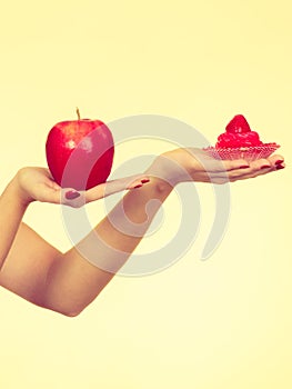 Woman hand holding apple and sweet cupcake