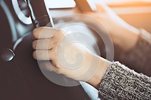 Woman hand holding on black steering wheel while driving a car