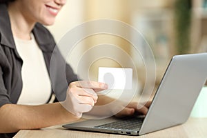 Woman hand holding blank credit card using laptop