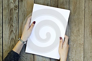 Woman hand holding blank paper on wooden table.