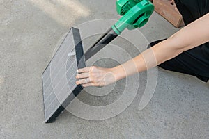 Woman hand holding blower to clean dirty air purifier