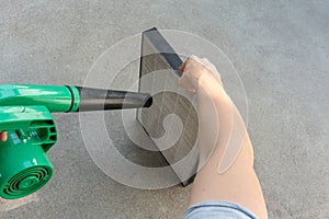 Woman hand holding blower to clean dirty air purifier