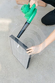 Woman hand holding blower to clean dirty air purifier