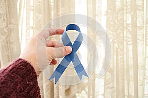 Woman hand holding blue ribbon, blue november conceot