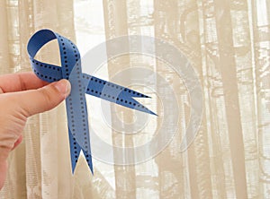 Woman hand holding blue ribbon, blue november conceot