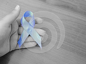 Woman hand holding blue ribbon, blue november conceot