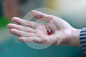 Woman hand holding capsule pills with pharmacy background