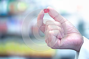 Woman hand holding capsule pills with pharmacy background