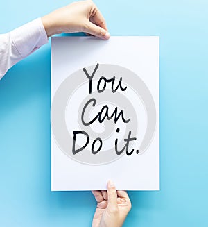 Woman hand holding card with the word you can do it isolated on blue background, studio shot. cheer and support quote