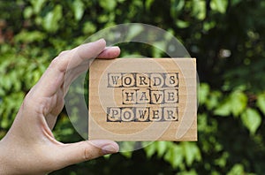 Woman hand holding cardboard card with phrase Words Have Power