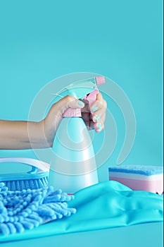 Woman hand holding cleaning spray blue plastic bottle detergent isolated on blue background with cleaning tools product supplies