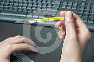 Woman hand holding clinical thermometer on working desk,After using the clinical thermometer and worry about coronavirus spread