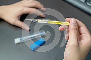 Woman hand holding clinical thermometer on working desk,After using the clinical thermometer and worry about coronavirus spread