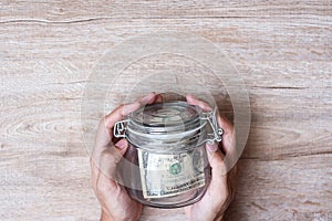 Woman hand holding coin money in glass jar. world saving day, business, investment, retirement planning, finance concept