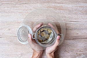 Woman hand holding coin money in glass jar. world saving day, business, investment, retirement planning, finance concept