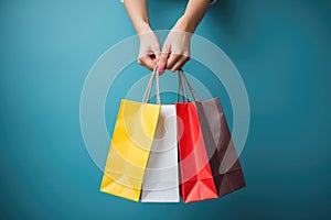 Woman hand holding colorful shopping bags on blue background. Shopping concept, Female hand holding many colorful shopping bags on