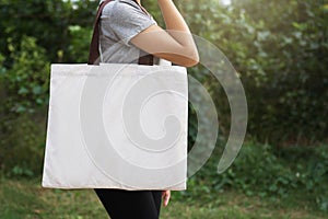 woman hand holding cotton bag on green background. eco