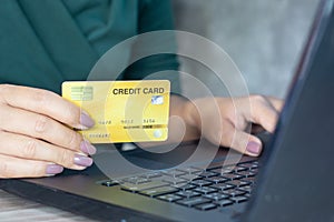 Woman hand holding credit card and typing on laptop keyboard for online shopping