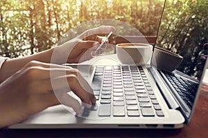 Woman hand holding credit card and use laptop vintage tone.