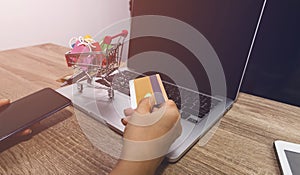 Woman hand with holding credit card and using laptop computer which she is pay money of shopping, e-commerce, internet