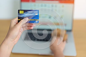 woman hand holding credit card and using laptop with mobile phone for online shopping while making order. Marketplace platform