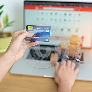 woman hand holding credit card and using laptop with mobile phone for online shopping while making order. Marketplace platform