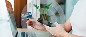 woman hand holding credit card and using laptop with mobile phone for online shopping while making order. Marketplace platform