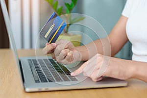 woman hand holding credit card and using laptop for online shopping while making order at home. Marketplace platform website,