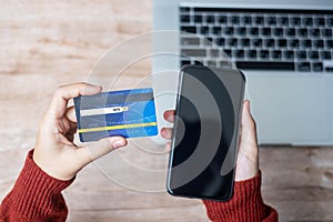 Woman hand holding credit card with using smartphone and laptop for online shopping while making orders at home. business,