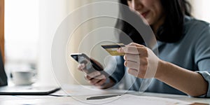 woman hand holding credit card with using smartphone for online shopping while making orders at home. business